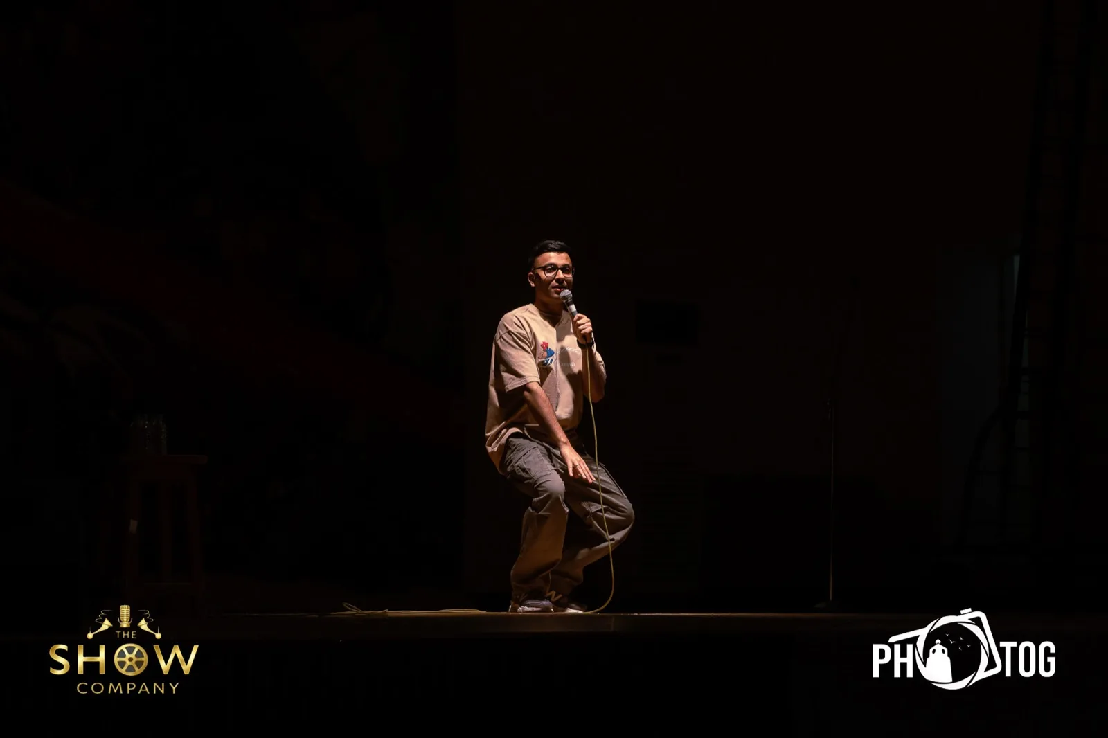 Comedian crouching with the mic during a live standup set